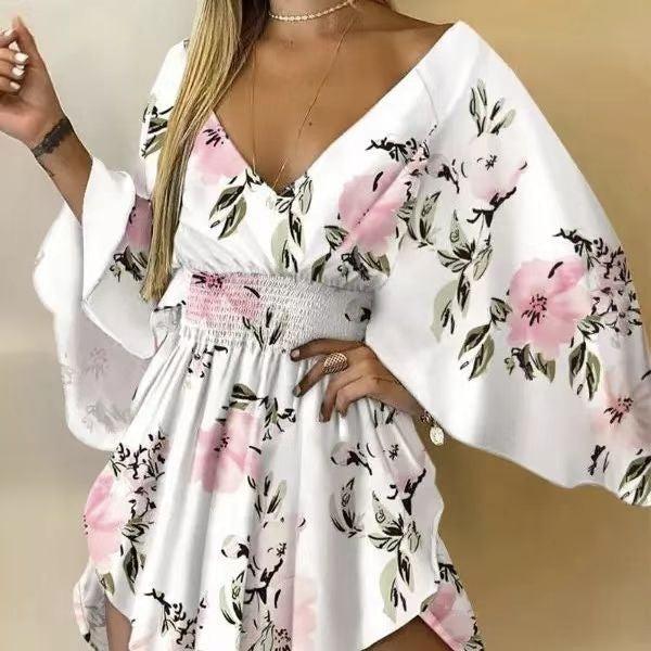 Woman wearing a white floral romper with wide kimono sleeves and pink flower print, featuring a smocked waist and V-neckline.

